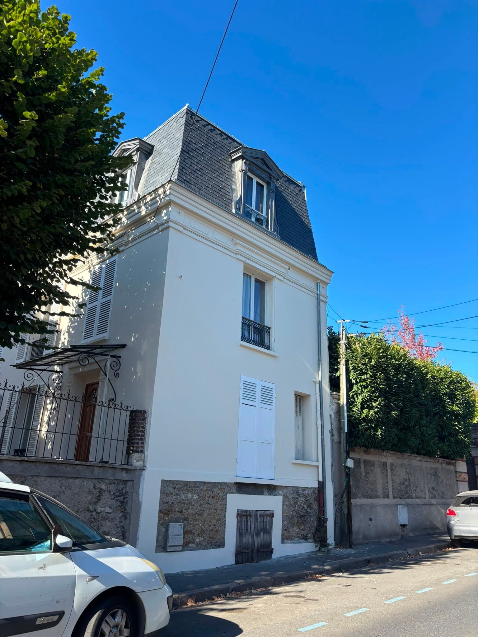 Maison au toit à la Mansart après travaux : façade ravalée et toiture en ardoises refaite